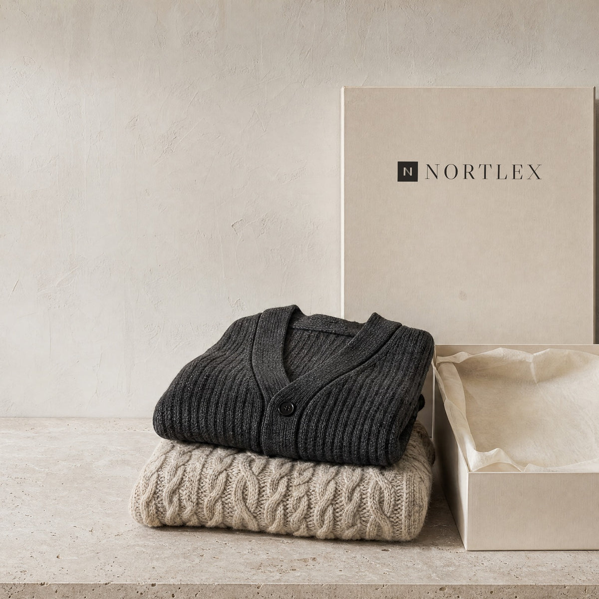 Folded knitwear beside an open Nortlex box lined with tissue paper